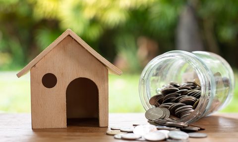 small wood house beside a coin jar to represent saving