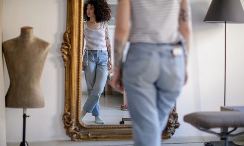 young woman standing in front of a vintage mirror