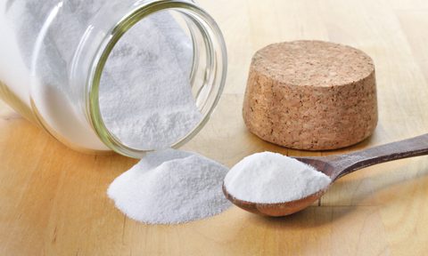 Glass jar of baking soda with cork and teaspoon tipped over