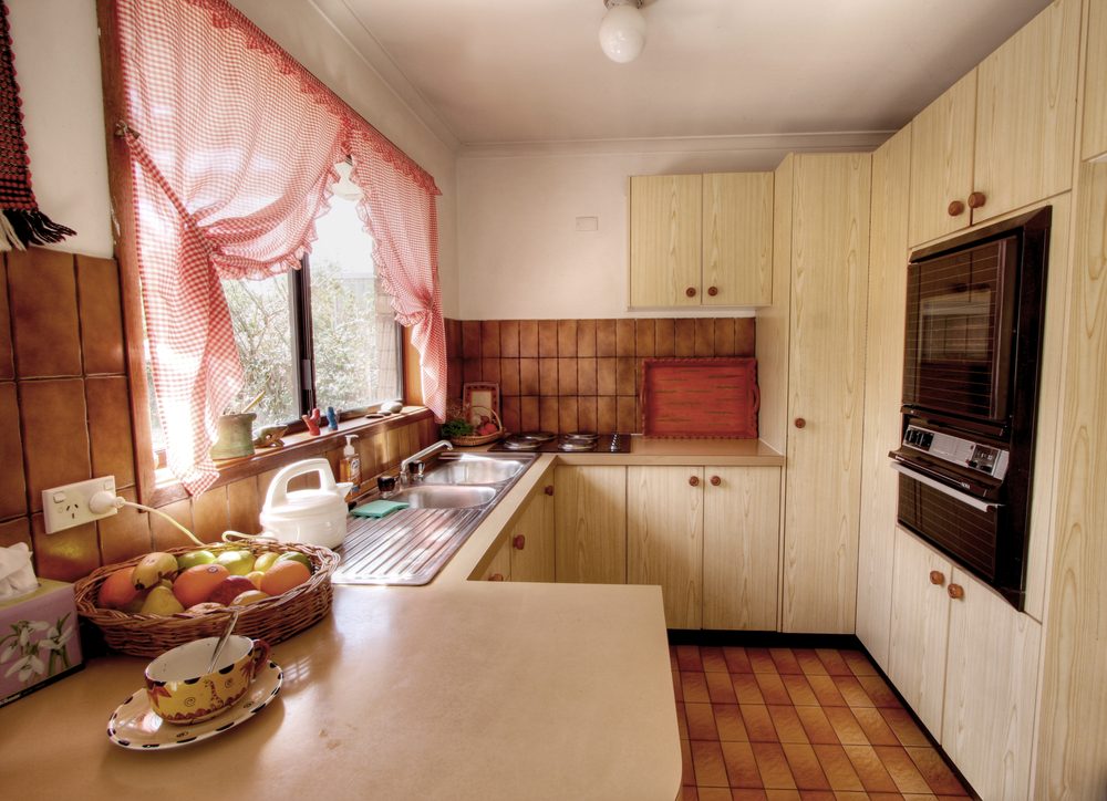 small outdated kitchen with window curtains