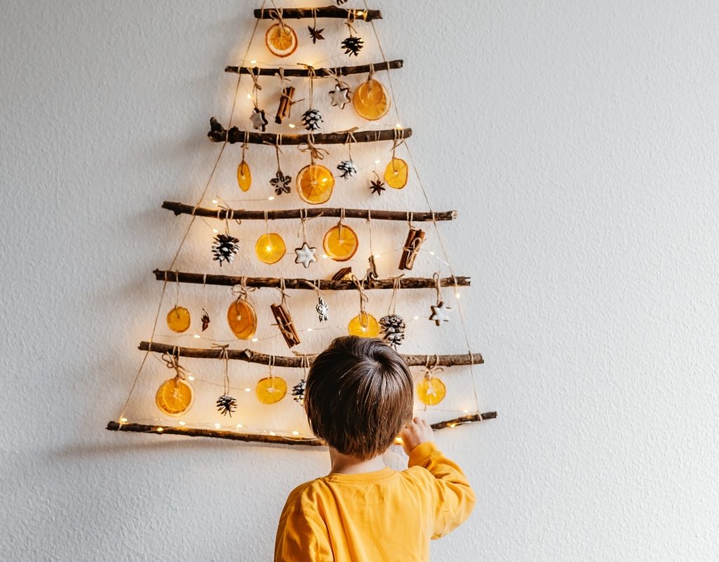 child putting up DIY wall-mounted christmas tree