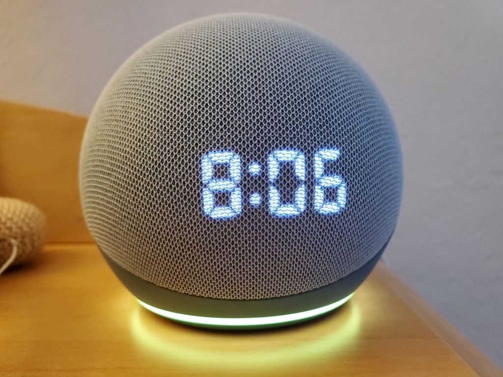 Close-up shot of the Amazon Echo Dot smart speaker with clock and Alexa on a night stand
