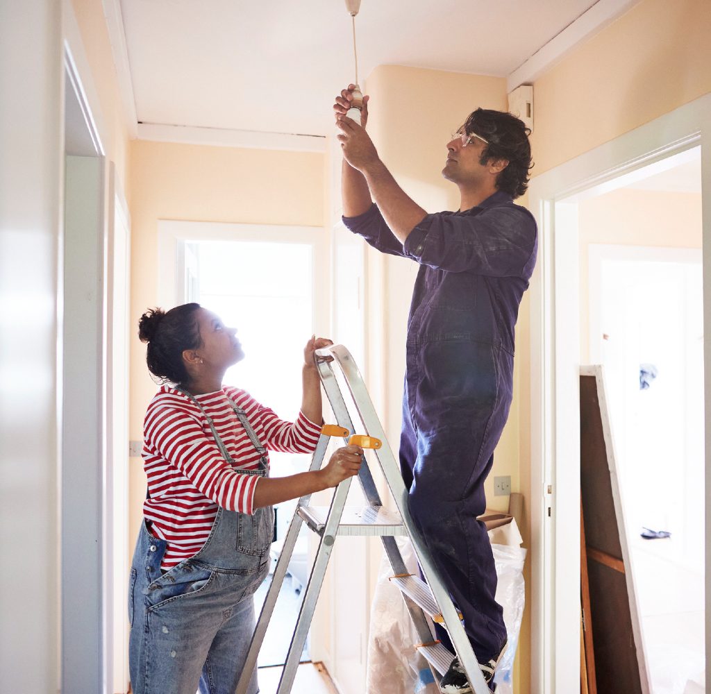 Couple replacing light fixture in home.