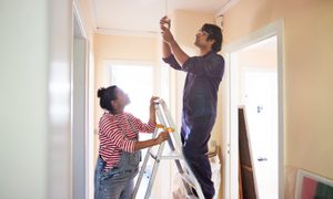Couple replacing light fixture in home.