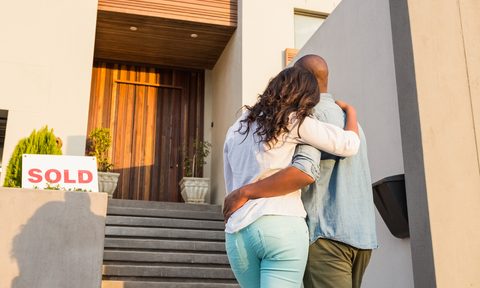 First-time homebuyers standing outside new home