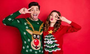 Man and woman wearing ugly Christmas sweaters