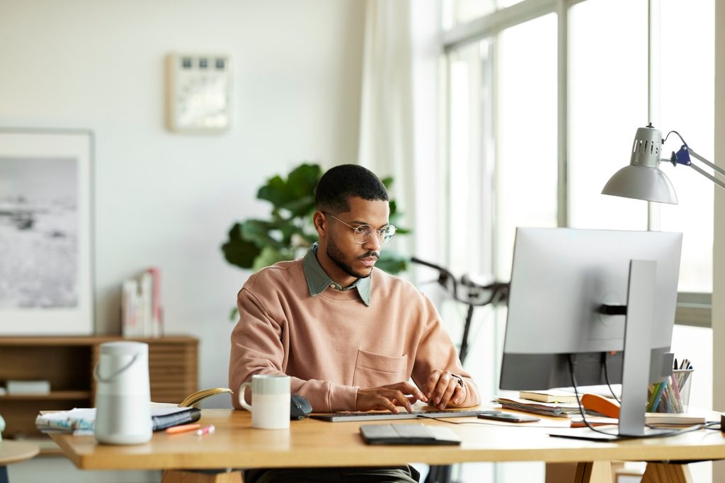 Man working at his computer on a desk in his home office