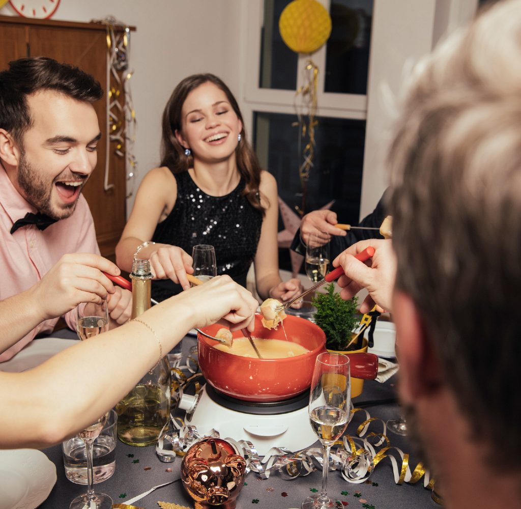 People celebrating New Year's Eve around kitchen table with fondu.