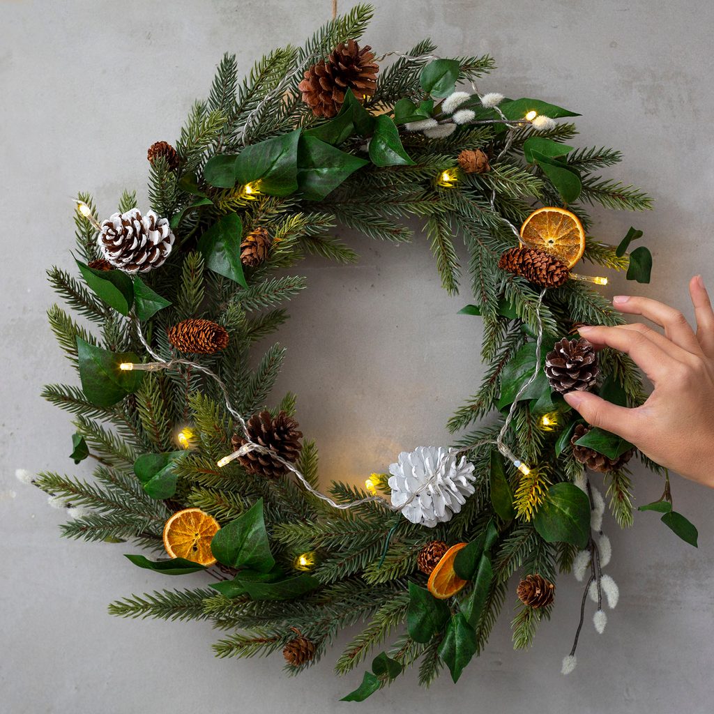 Person adjusting a winter wreath