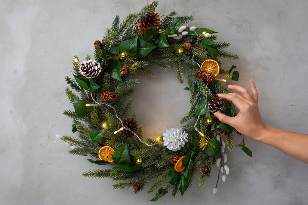 Person adjusting a winter wreath