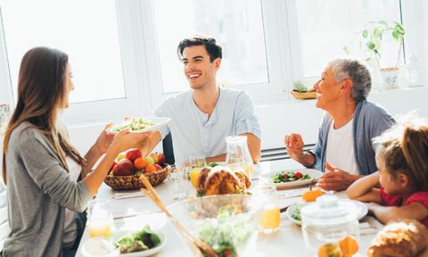 Family eating Thanksgiving dinner with salad.