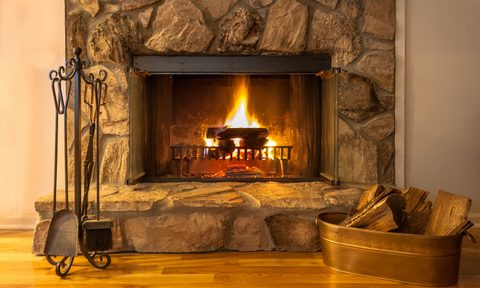 lit fireplace with rack of tools and bin of wood