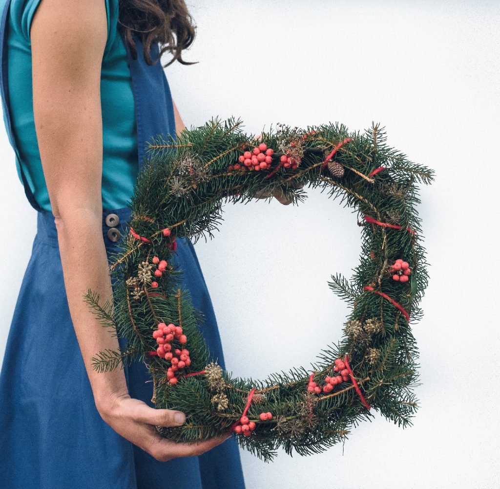 Woman holding Christmas wreath made of real trees