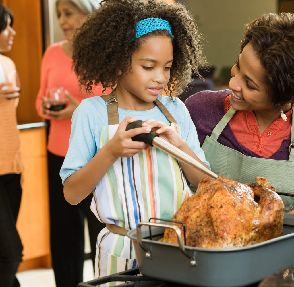 Woman and child basting Thanksgiving turkey.