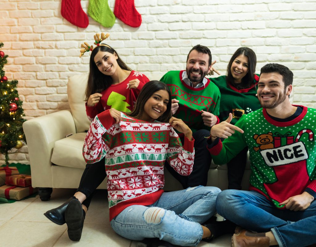 Group of people wearing ugly Christmas sweaters in a living room