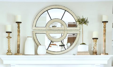 All-white mantle with mirror, candles, and pottery.