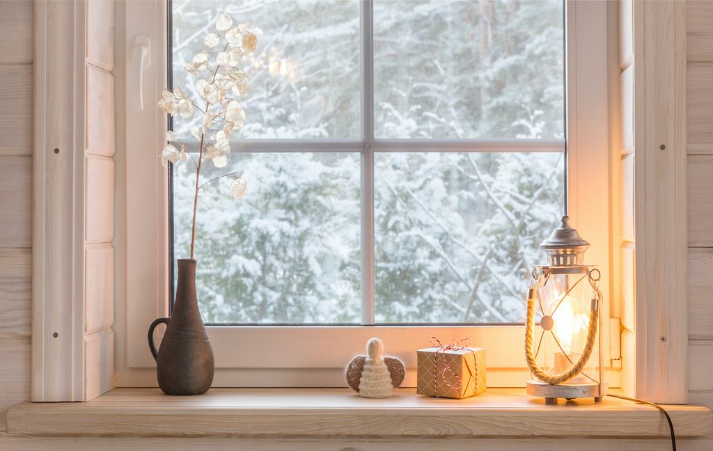 Beautiful burning candles and fairy lights on windowsill indoors with vase