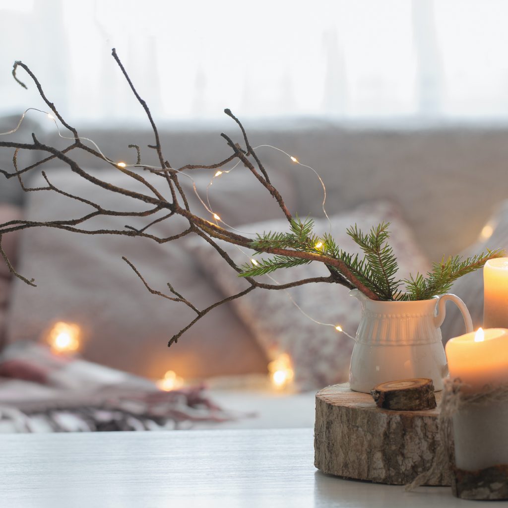 Composition of candles on white table against the background of a sofa