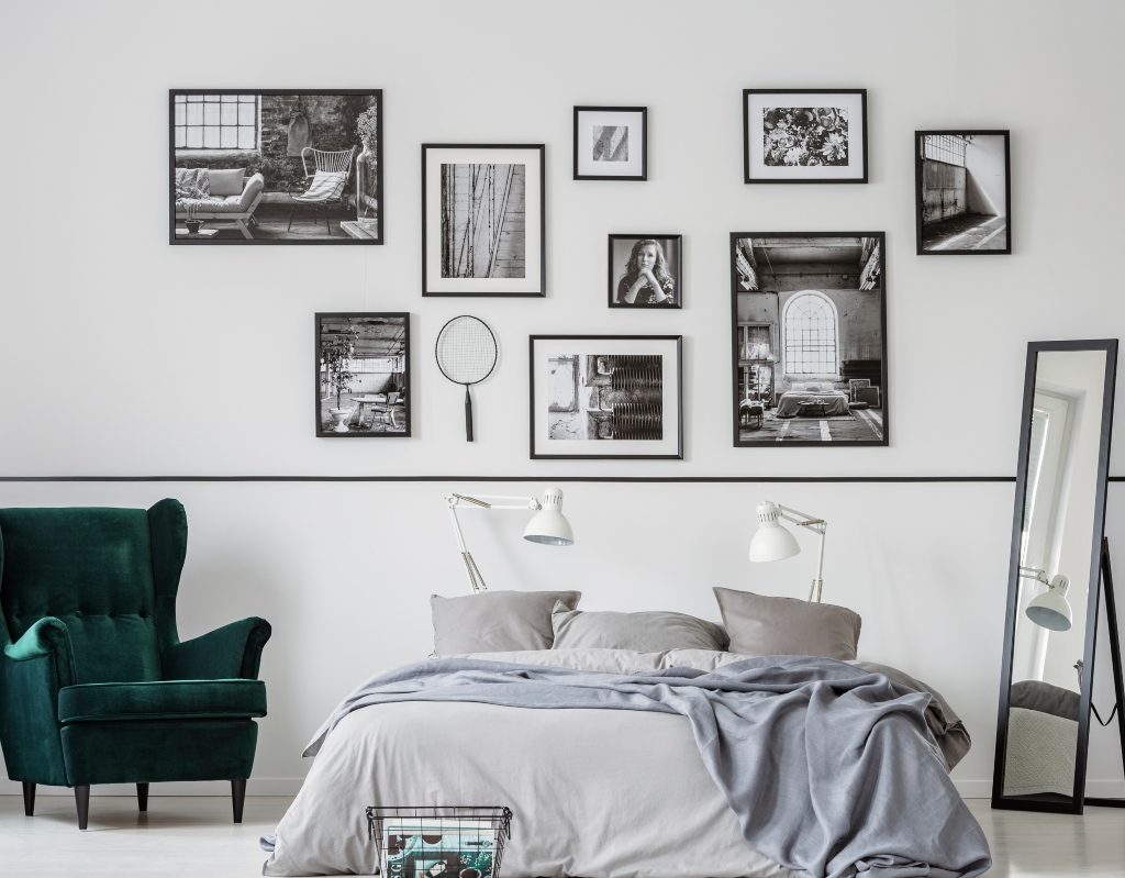 Gallery wall above bed with black and white frames and small mirror