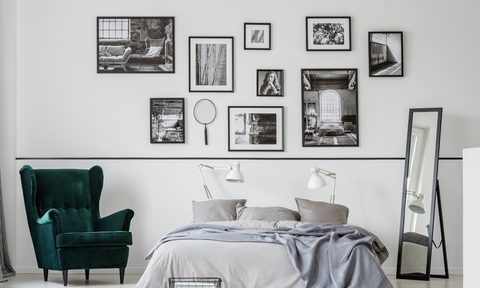 Gallery wall above bed with black and white frames and small mirror