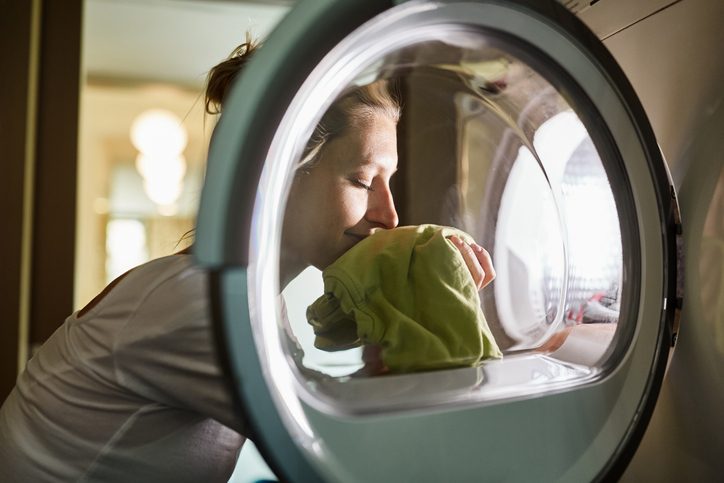 Woman smelling freshly dried clothes in front of dryer