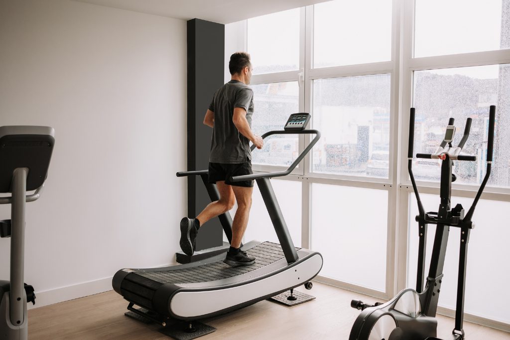 Man running on treadmill in home gym.