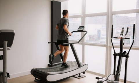 Man running on treadmill in home gym.