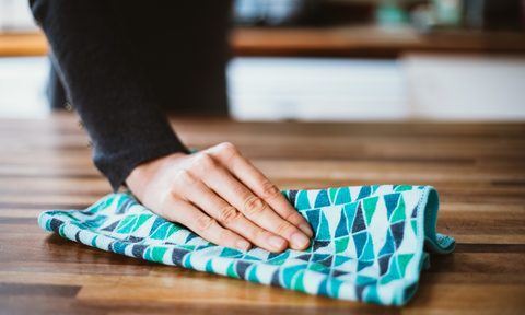 Person's hand using cloth to wipe down a counter surface