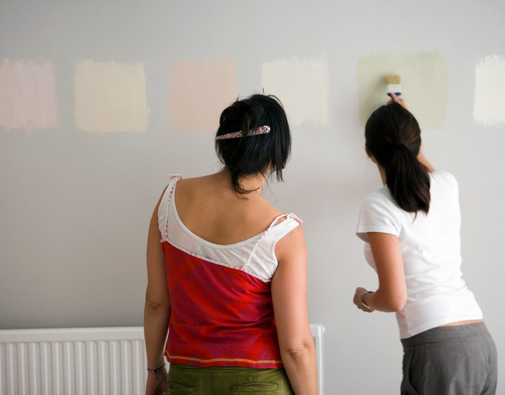 two women using paint samples on wall