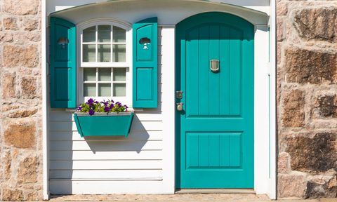 teal front door of small white cottage