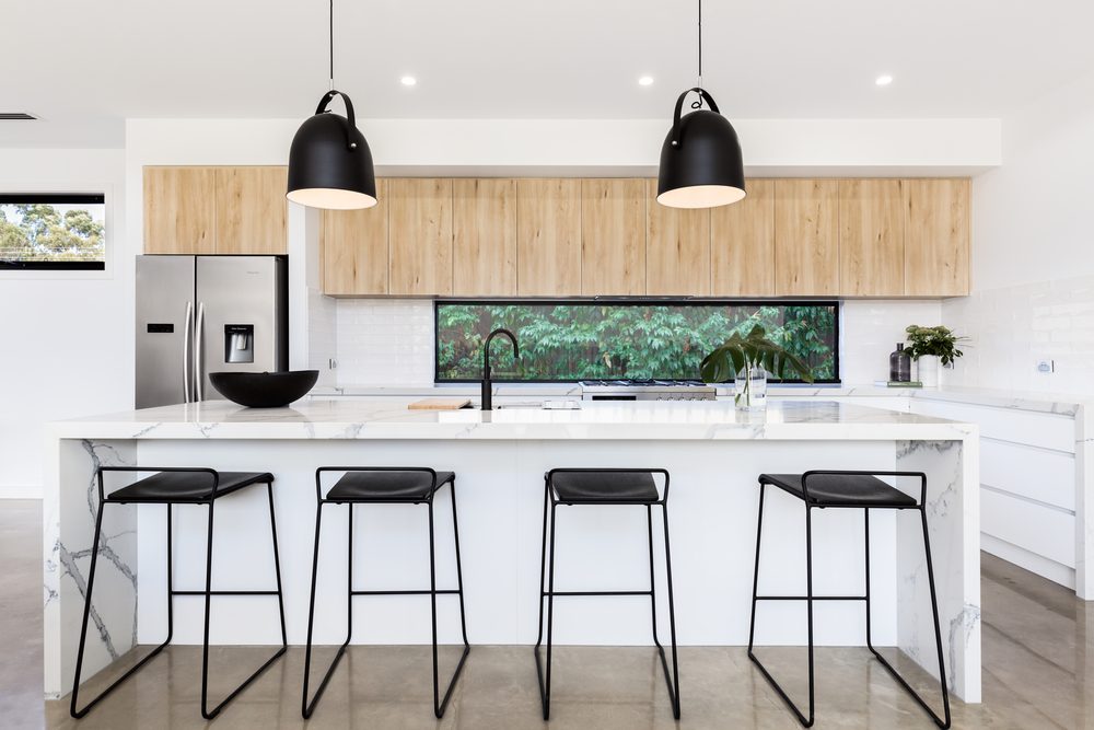 White modern kitchen with black pendant lights and black stools
