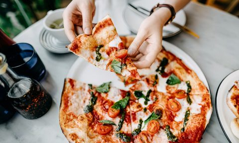 Person eating Margherita pizza.