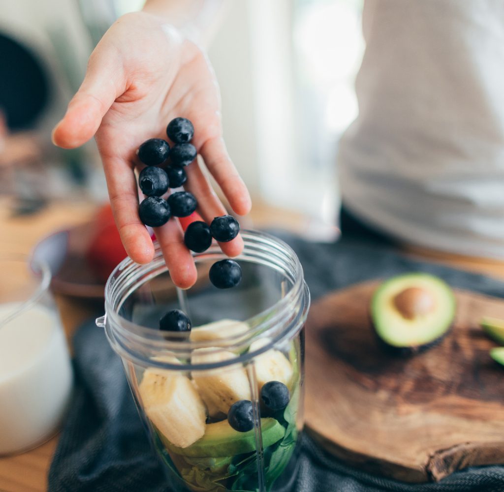 Person making smoothie with fruits.