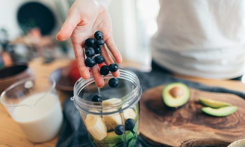 Person making smoothie with fruits.