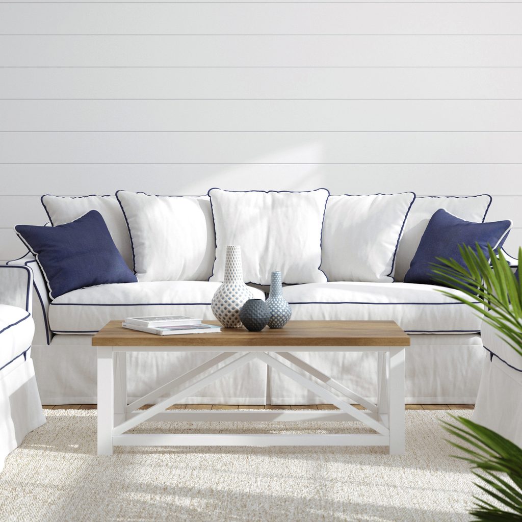 White sofa with navy accents in front of shiplap wall