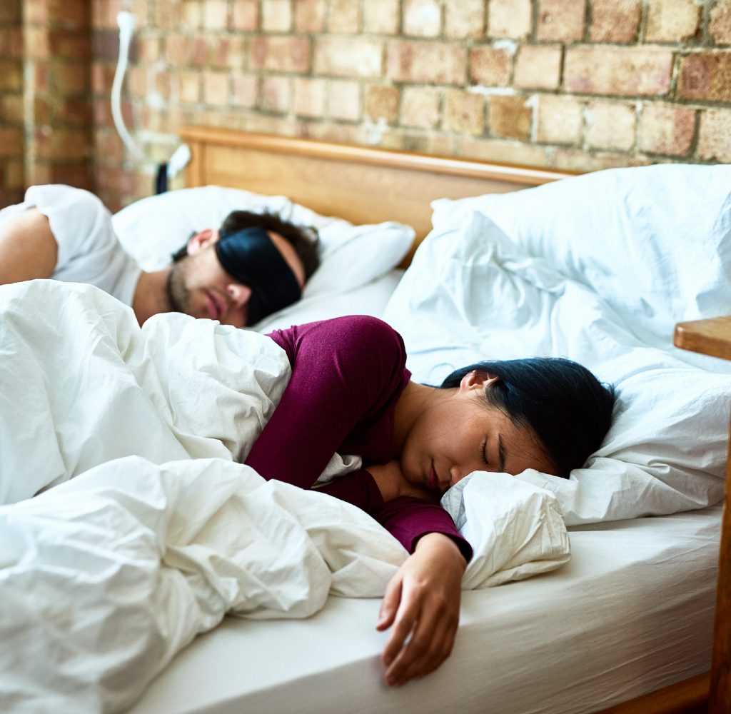 Couple sleeping comfortably in bed.
