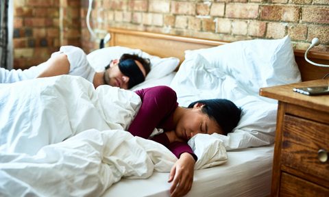 Couple sleeping comfortably in bed.