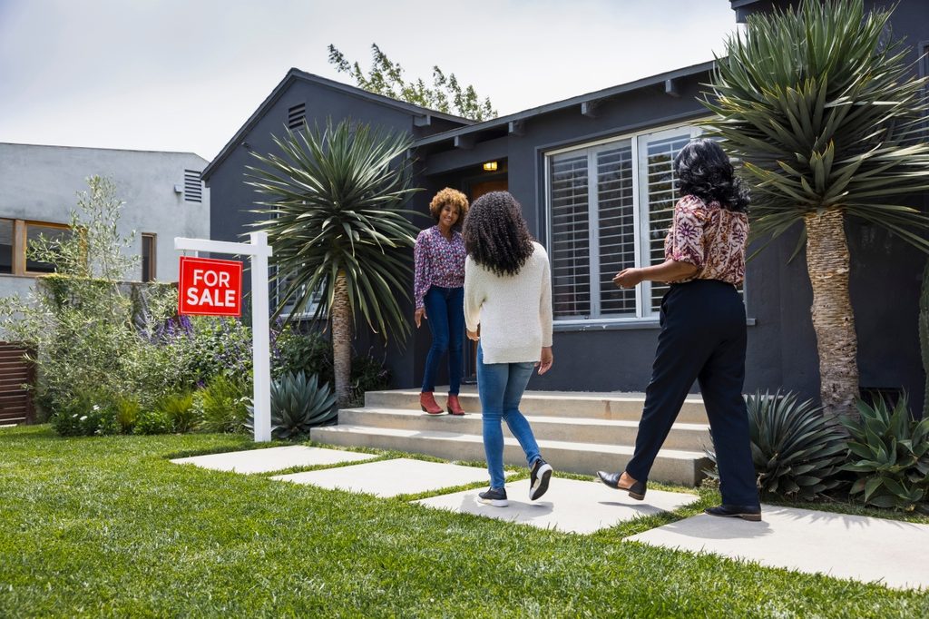 people attending a home showing with for sale sign
