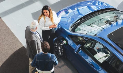 what to consider when buying an electric car high angle view of saleswoman showing customers at showroom
