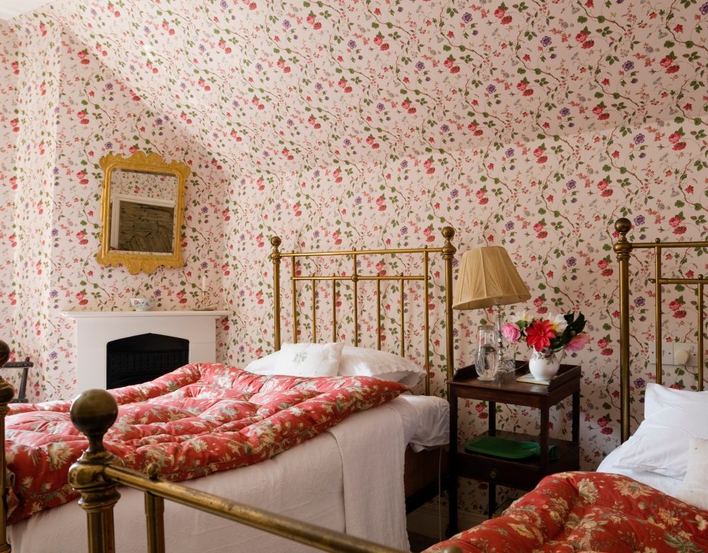 grandmillenial bedroom with two beds and patterned wallpaper