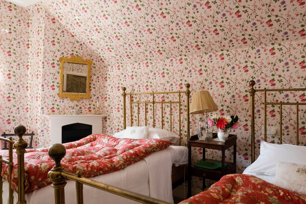 grandmillenial bedroom with two beds and patterned wallpaper