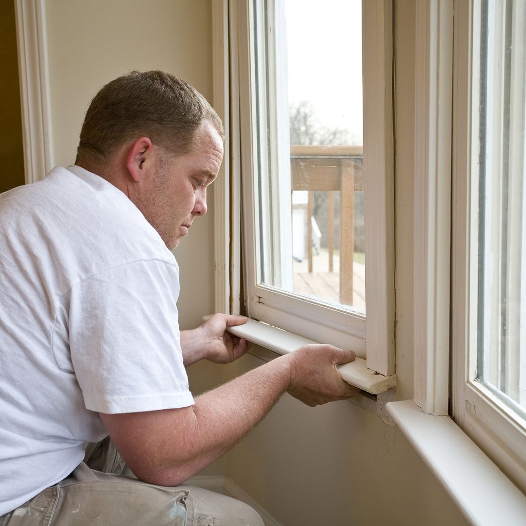 Man installing bottom of window trim