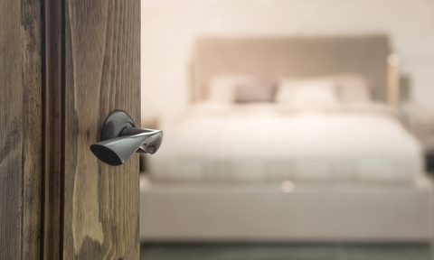 Close-up of door handle with bed out of focus in the background