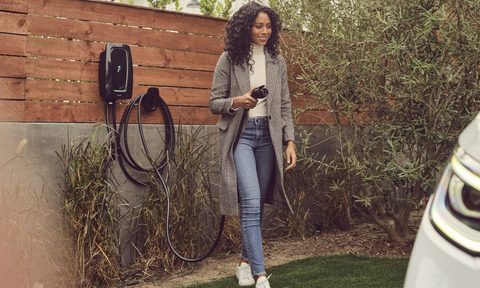 Young woman walking to EV with charging cord