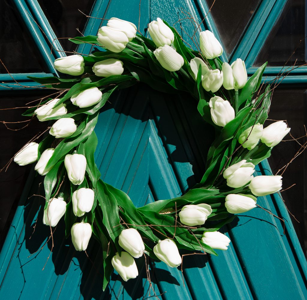 Spring wreath made from white flowers on a teal door