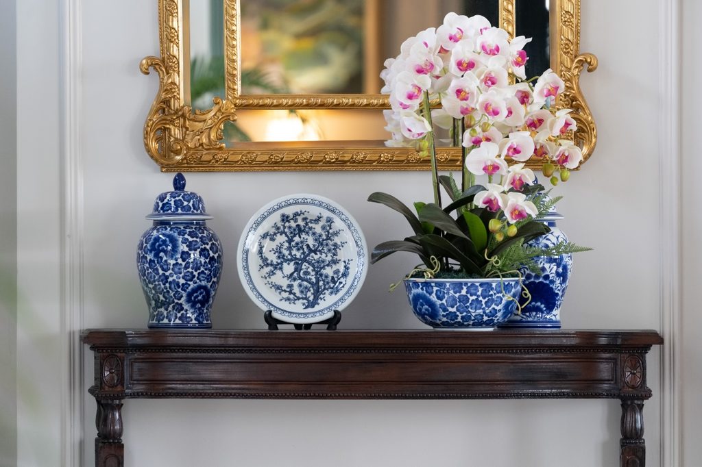 Blue and white porcelain plate decor on entryway table with flowers