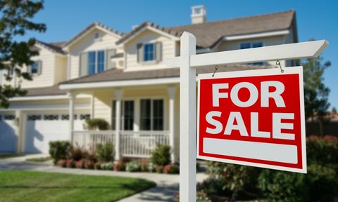 Cream-colored suburban home with for sale sign