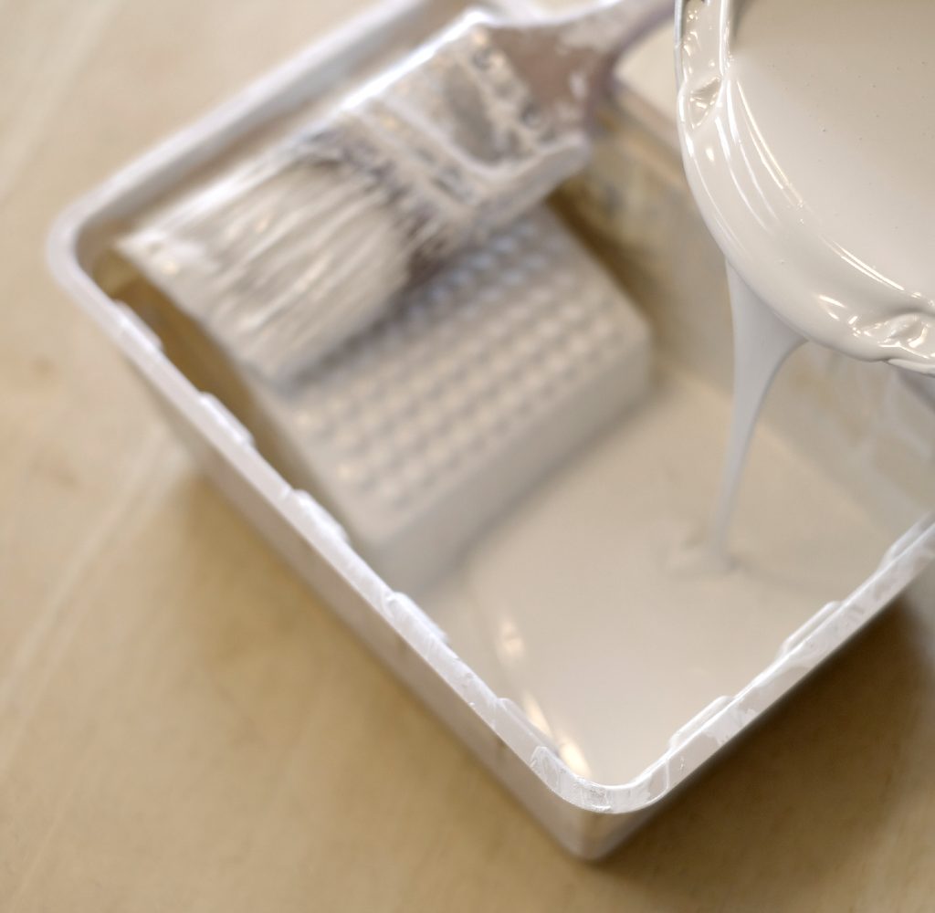 Pouring cream paint into a paint tray