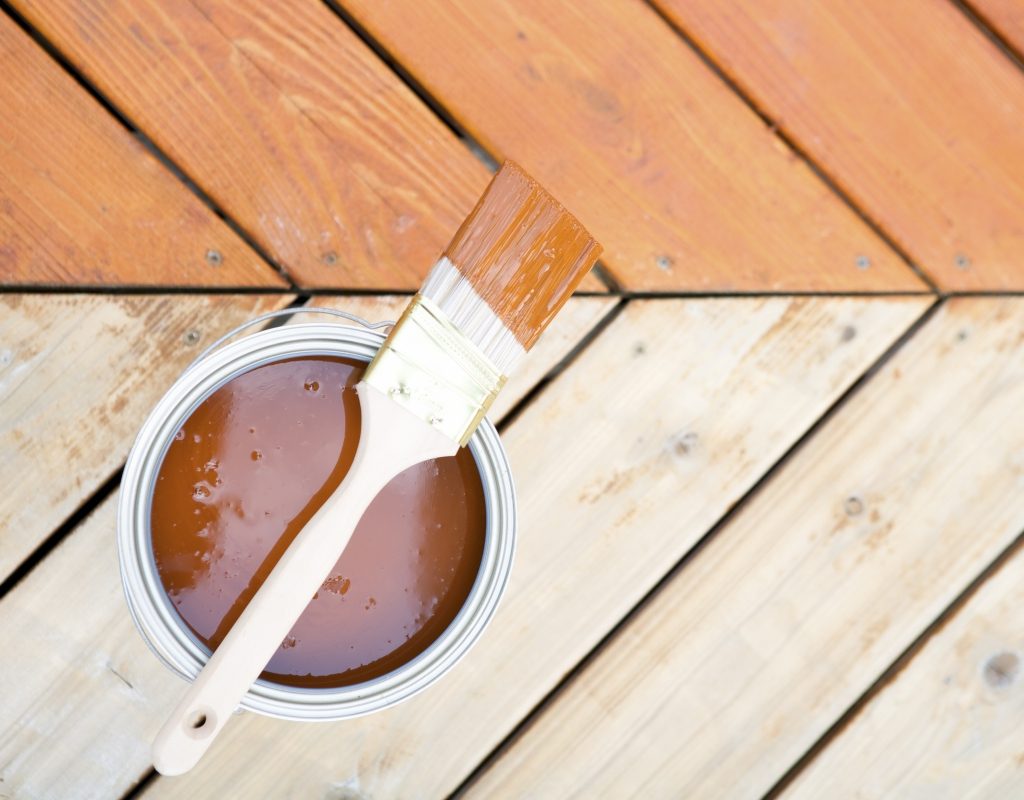 wood stain in can with brush on wood decking