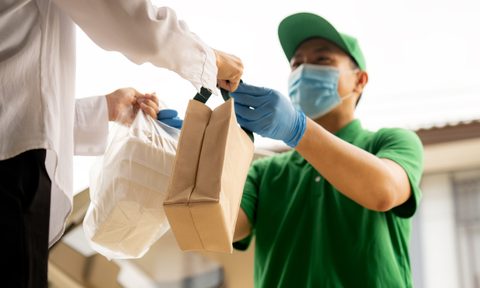 Delivery driver delivering bags of food to a man.